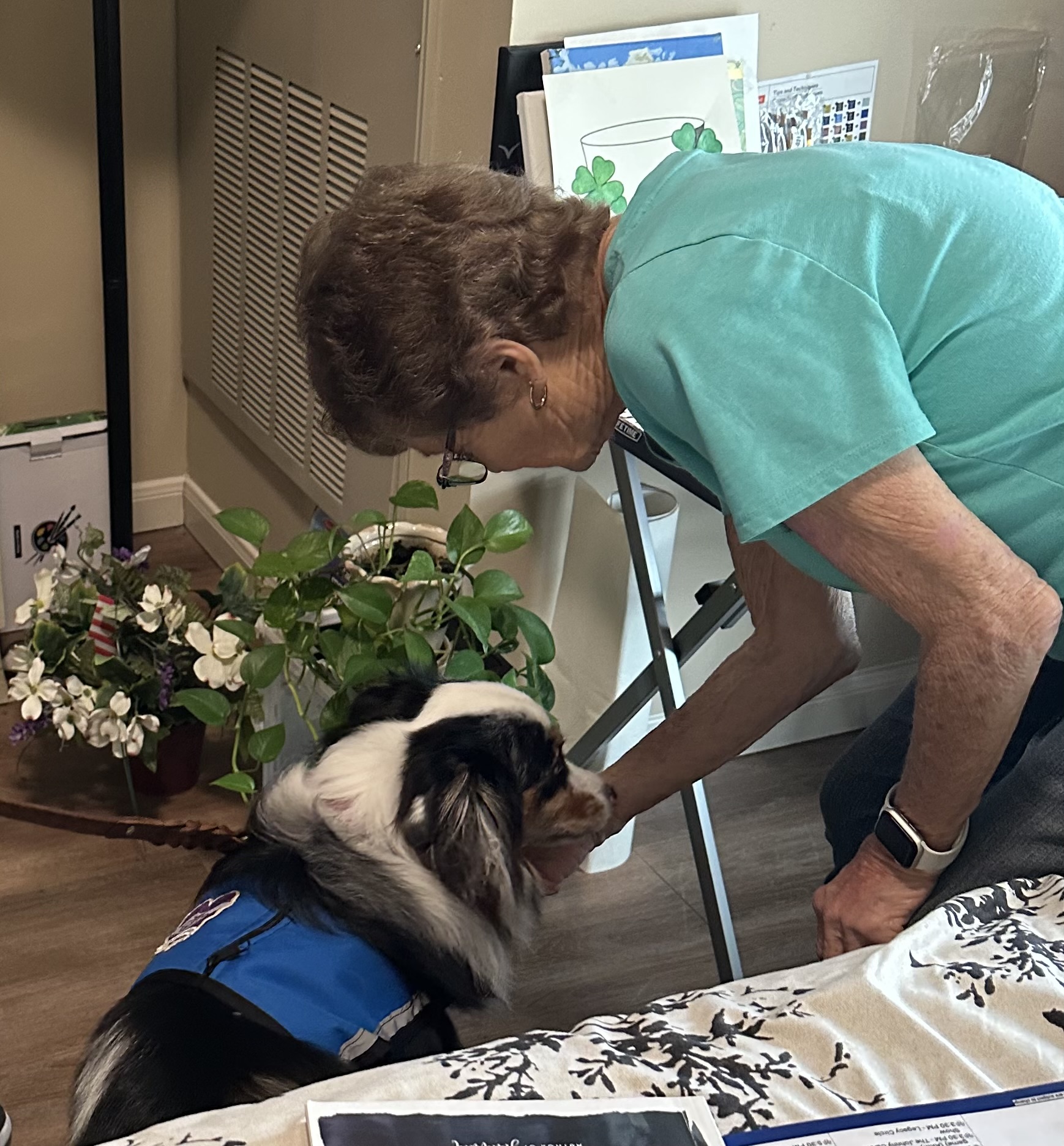 A resident petting Boo the Australian shepherd therapy dog during a visit