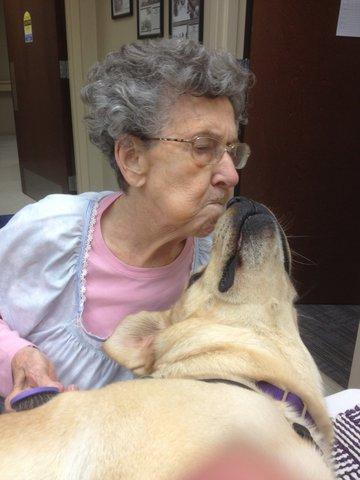An older woman sharing a kiss with therapy dog Ian
