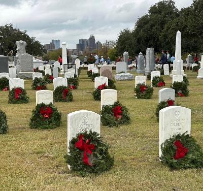 Rows of headstones with holiday wreaths at San Antonio National Cemetery