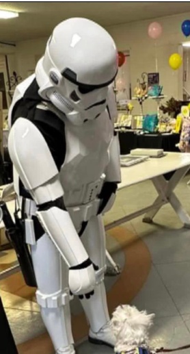 A Storm Trooper greeting a small white therapy dog