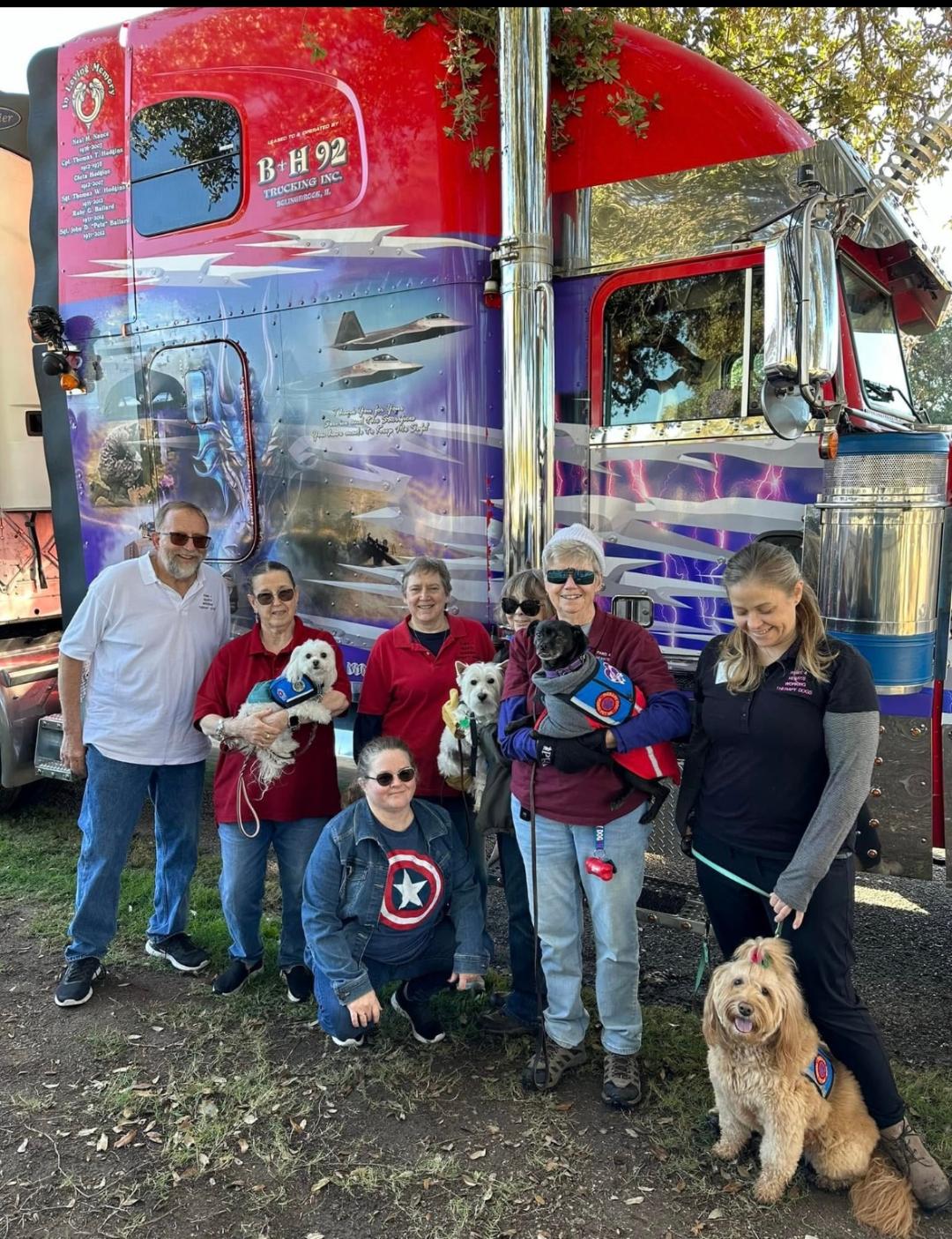 Paws 4 Hearts volunteers with their therapy dogs in front of a memorial truck at Wreaths Across America